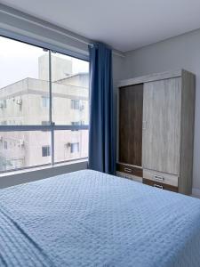 a bedroom with a bed and a large window at Residencial Spader - Bombinhas in Bombinhas