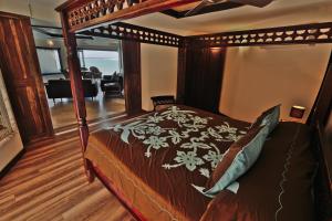 a bedroom with a canopy bed with a living room at Reflections On Rarotonga in Rarotonga +13 photos