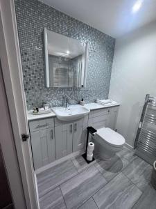 a bathroom with a toilet and a sink and a mirror at ROSE-WOOD Gatwick in Horley