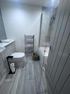 a bathroom with a toilet and a sink and a tub at ROSE-WOOD Gatwick in Horley