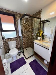 a bathroom with a toilet and a shower with purple rugs at Bangalô aconchegante e luxuoso Winterville Resort Gravatá PE in Gravatá +45 photos