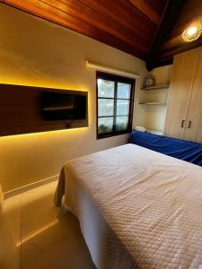 a bedroom with a white bed and a window at Bangalô aconchegante e luxuoso Winterville Resort Gravatá PE in Gravatá