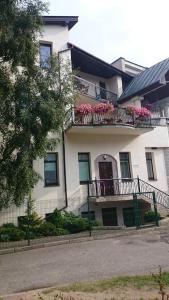 a white house with pink flowers on a balcony at Atgiris in Palanga