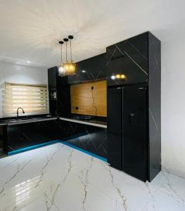 een keuken met zwarte kasten en een marmeren vloer bij D-Lezzubra Luxury Apartments in Gwarinpa +14 foto's