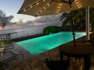 a swimming pool with an umbrella next to the ocean at Birdies Nest Upper 2 Bedroom Beach View in Black Rock