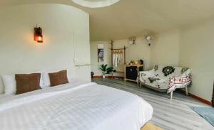 a bedroom with a white bed and a chair at บ้านไร่นายสิงห์-Banrainaysing in Ban Huai Khai
