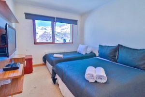 Una habitación de hotel con dos camas y un televisor. en HOM Frente a la cordillera depto 7PAX Cerca de las Pista de SKY, en Lo Barnechea