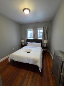 a bedroom with a large white bed and two windows at The Maverick Upstairs - NEW! - Lux Apartment - 2 Miles From Airport & Downtown Boston in Chelsea