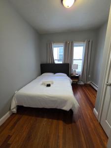 a bedroom with a bed with white sheets and wood floors at The Maverick Upstairs - NEW! - Lux Apartment - 2 Miles From Airport & Downtown Boston in Chelsea
