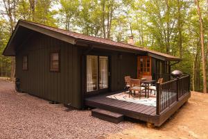 une petite cabane verte avec une terrasse et une table dans l'établissement Romantic Mountainside Cozy Cabin Poconos, à Gouldsboro