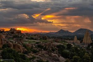 a sunset over a city with rocks and temples at Hampi's Dream Cottage in Hampi