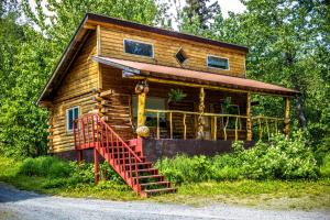 a log cabin with a red staircase in front of it at Midnight Sun Log Cabins in Moose Pass