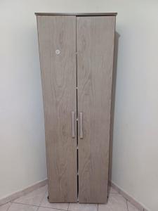 ein Holzschrank mit zwei Türen in einem Raum in der Unterkunft Quarto Luz in João Pessoa
