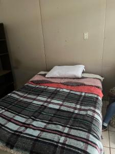 ein Bett in einem Zimmer mit einer Decke darauf in der Unterkunft La casa del buen paso in San Lorenzo