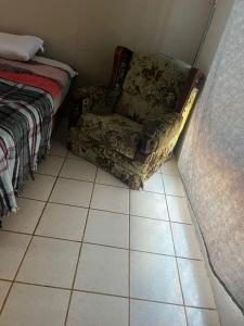 ein Stuhl, der auf einem gefliesten Boden neben einem Bett steht in der Unterkunft La casa del buen paso in San Lorenzo