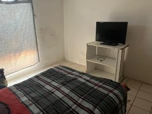 Schlafzimmer mit einem Bett und einem Schrank mit einem TV in der Unterkunft La casa del buen paso in San Lorenzo