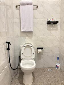 baño con aseo blanco y toalla en Hostel Labuan ORA, en Labuan Bajo