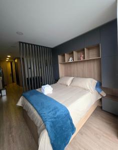 a bedroom with a large bed with a blue blanket on it at Loft Panorámico con estilo, Coworking-Gym, Usaquén in Bogotá