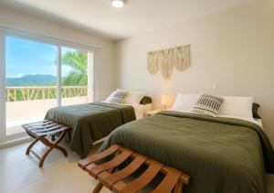 two beds in a room with a window at 2 Rec Vista a las Montañas I Amplia Terraza I Smart TV-Netflix I Wi-Fi I Recién Remodelado in Ixtapa