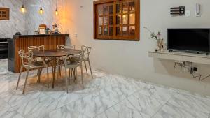 a dining room with a table and chairs and a tv at Chalé Recanto dos pássaros. in Guaraciaba do Norte