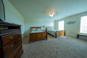 a bedroom with two beds and a dresser and a tv at Inshore Paradise Steps from the marsh 