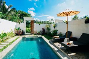 a swimming pool in a backyard with an umbrella at Evandari villa in Ubud