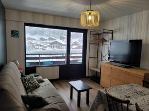 un salon avec un canapé et une grande fenêtre dans l'établissement Studio cosy 4/5 pers, pied des pistes, balcon exposé ouest - FR-1-458-253, au Chinaillon