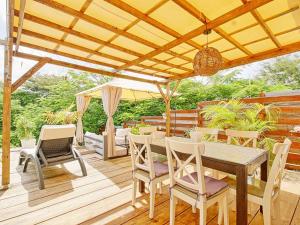 une terrasse en bois avec une table, des chaises et un parasol dans l'établissement Cocotier Charme, Confort & Détente près dOrient Bay - FR-1-734-78, à Cul de Sac