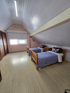 a attic room with a bed and a couch at Casa 3 suítes no Centro de Canela in Canela