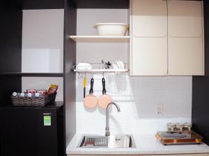 a kitchen with a sink and a black refrigerator at Be Staycation Sai Gon in Ho Chi Minh City