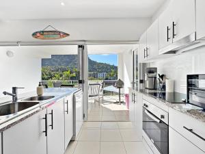 a kitchen with white cabinets and a view of a patio at Beachside 17 in Nelly Bay