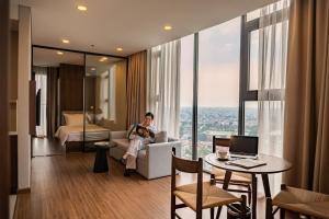 a woman sitting on a couch in a hotel room at Mandala Hotel & Suites Hải Dương in Bảo Thap