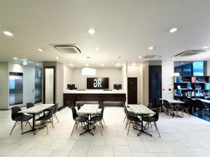 a dining room with tables and chairs and a tv at Green Rich Hotel Iwakuni Ekimae (Artificial hot spring Futamata Yunohana) in Iwakuni
