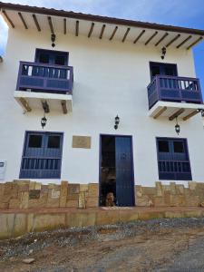 un cane è seduto sulla soglia di una casa bianca di IL CASTELLO DI LETTERE Barichara a Barichara