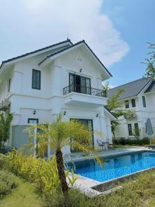a white house with a swimming pool in front of it at Biệt thự Đế Liên nguyên căn 2 tầng- Vườn Vua Resort Phú Thọ in Ðồng Phú