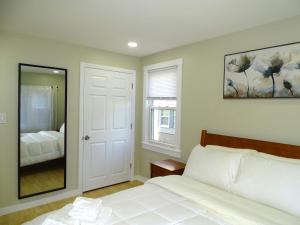 a bedroom with a white bed and a mirror at Comfortable Renovated 3 Bed Apartment in Framingham +16 photos