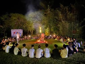 a group of people sitting around a fire at night at AQUARIUS GARDEN NINH BÌNH in Giá Sơn +52 photos