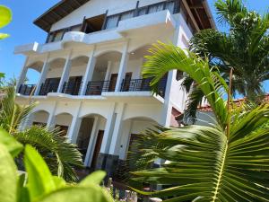 a white building with palm trees in front of it at Kutabay Homestay in Kuta Lombok