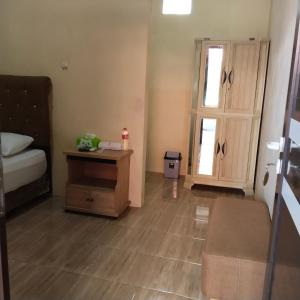 a bedroom with a bed and a table and a door at Ayna Guest House Syariah Indramayu in Kepandean +2 photos