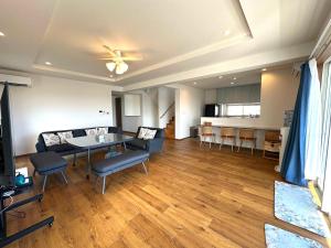 a living room with a table and chairs and a kitchen at Beach house Yomitan 都屋別館 in Yomitan