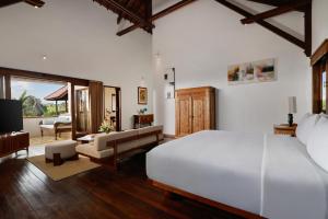 a bedroom with a white bed and a living room at Villa Tropical Svasti by Nakula in Canggu
