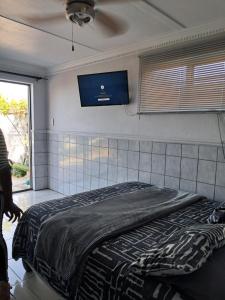 a bedroom with a bed with a tv on the wall at Lion's Cave 2 in Mossel Bay