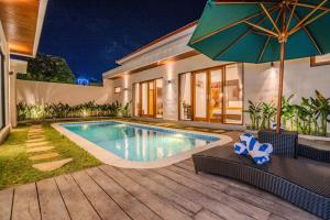 una piscina en el patio trasero de una casa con sombrilla en Villa Radha Seminyak, en Seminyak