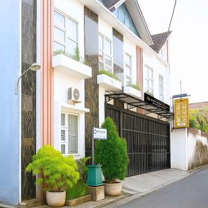 a white building with a black gate and some plants at Djuragan Kamar Dmangkoe in Bonorejo