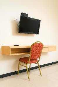 a chair sitting in front of a desk with a tv at Djuragan Kamar Dmangkoe in Bonorejo