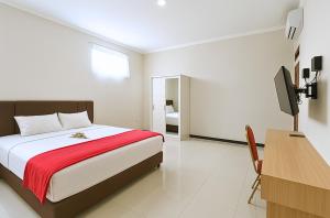 a bedroom with a bed and a desk and a television at Djuragan Kamar Dmangkoe in Bonorejo