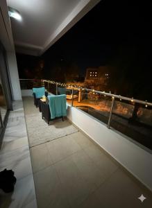 a balcony with two chairs and a table at night at Luxury Stay in Prestigia Golf City in Bouskoura