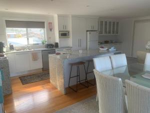 a kitchen with a table and a kitchen with white cabinets at Noble House in Tathra