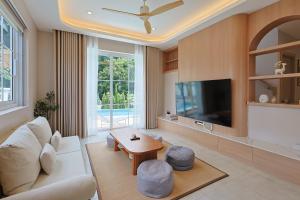a living room with a white couch and a tv at White Wood Family Villa, 5 Kingbeds, 12 mins airport in Chiang Mai