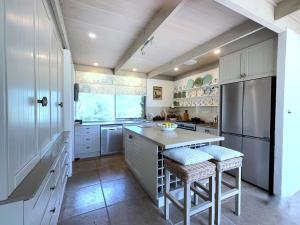 a kitchen with white cabinets and a large island with stools at Foxwood - Romantic French Style Country Retreat in Foxground +17 photos